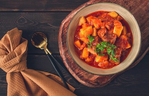 Stew with potatoes, in tomato sauce, with spices and herbs, close-up, no people, on a black