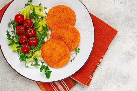 Crispy fried fish cutlets, fish burgers, on a white plate, with fresh lettuce leaves, arugula and