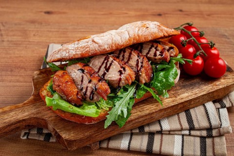 Sandwich with duck breast and arugula, balsamic sauce, on a wooden chopping board, breakfast,