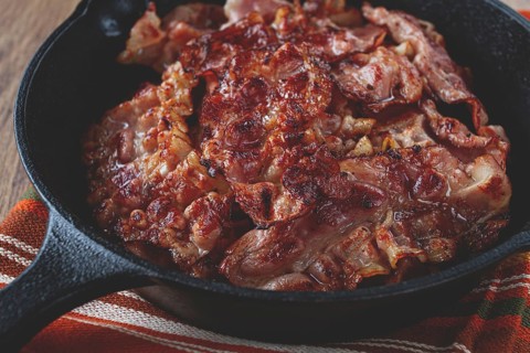 Crispy bacon, on a cast-iron skillet, on a wooden table, rustic style, no people