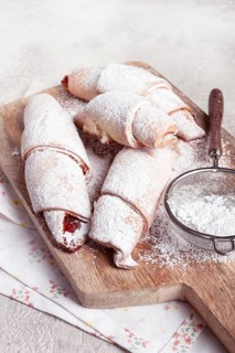 Bagels with filling, sweet pastries, sprinkled with powdered sugar, on a wooden board, dessert,