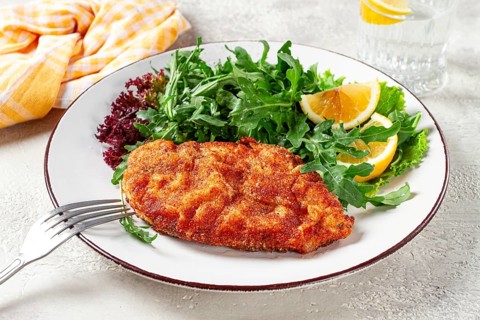 Milanese chicken, Crispy breaded chicken served, with fresh herbs, and lemon wedges