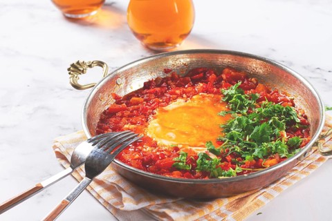 Traditional Turkish dish, scrambled eggs with tomatoes, Menemen, with herbs, in a frying pan,