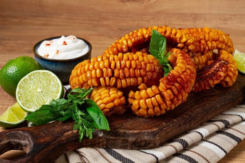 Corn ribs, with cream sauce, spices and lime, appetizer, on a wooden cutting board, homemade, no