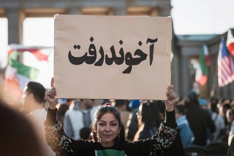 A woman holds up a sign with the inscription The Mullah Went during the demonstration by exiled