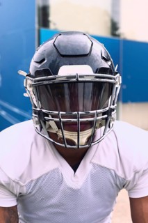 An American football player dressed in full uniform and helmet, ready for action. The scene