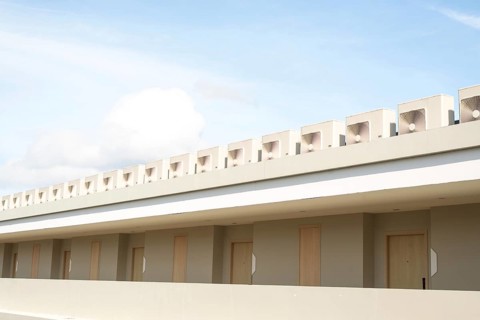 A minimalist building showcases its clean lines and neutral tones under a bright blue sky with