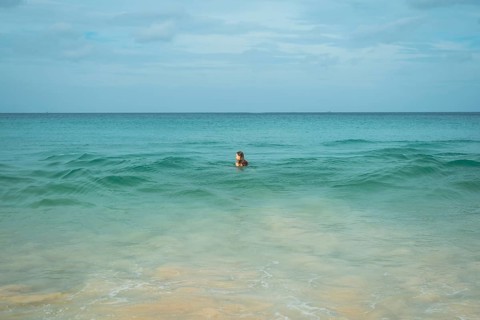 A young woman enjoys a swim in the clear turquoise waters of a tranquil beach in vacation, creating