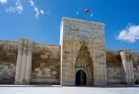 Historic fortress entrance with two flags under a cloudless sky, portal of the Sultanhani