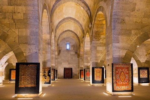 Large stone hall with illuminated carpets between imposing arches, Sultanhani caravanserai, on the