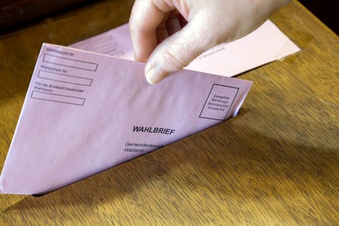 Absentee voting symbol: A ballot letter is thrown into the ballot box of a municipal administration