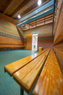 A light-flooded changing room with wooden benches and brick walls, turquoise floor, Schlehengäu