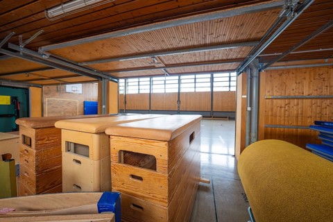 Storage room in a gym with stored sports equipment and wooden paneling, Schlehengäu Grund Schule