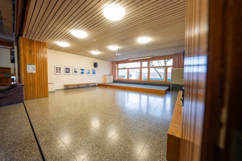 Another common room with parquet floors, wooden walls and large windows, decorated with picture