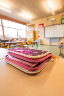 A pencil case is lying on a school desk in the classroom, blurred background, Schlehengäu Grund