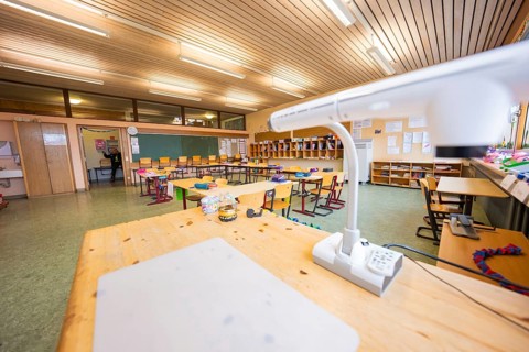 Teacher's desk in a well-lit classroom with blackboards and organized chairs, Schlehengäu Grund