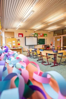 Classroom with colorful paper chains and blackboards, equipped with wooden school desks,