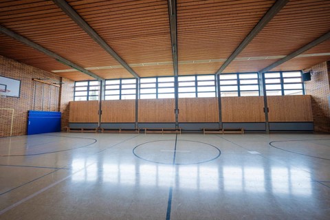 Large, empty gym with wooden floors and windows that let in natural light, Schlehengäu Grund Schule