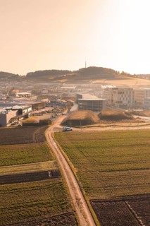Rural road leads to large buildings in morning light over fields, new hospital at Calw health