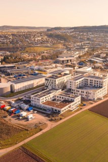 Aerial view of an industrial plant with modern buildings and surrounding fields in warm sunlight,