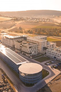 Modern buildings with solar panels in an urban environment surrounded by picturesque fields, new