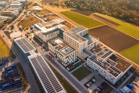 Modern buildings with solar panels surrounded by agricultural fields and industrial areas, new