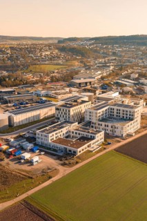 Panoramic view of an urban environment, modern buildings and surrounding fields in morning light,