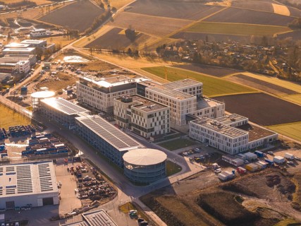 Spacious modern building complexes on the outskirts of a city surrounded by fields, new hospital on