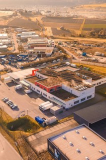 Industrial complex with warehouses and vehicles on the outskirts of a city, new hospital on the