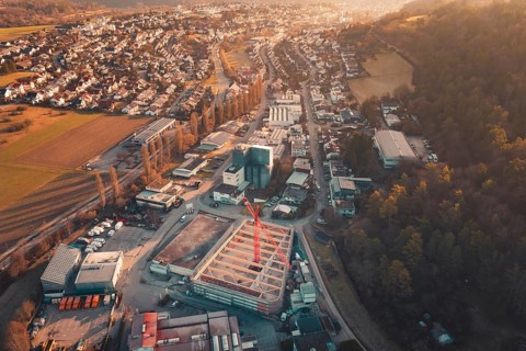 Panoramic view of an urban building area with crane and surrounding residential areas at sunset,