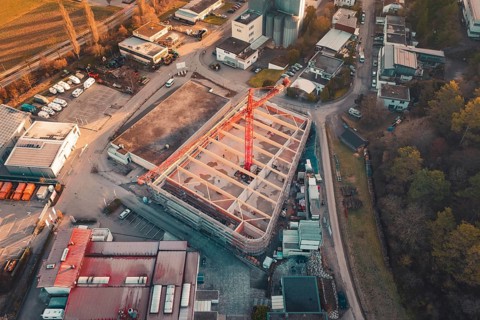 Aerial view of a construction site with crane in an urban area at sunset, surrounded by buildings