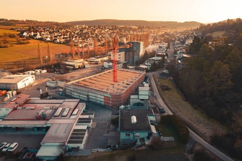 Urban scene with construction crane surrounded by residential areas and rolling hills at dusk,