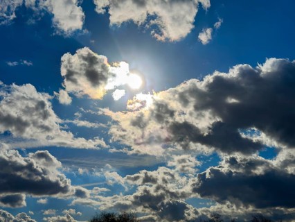Looking at the sun behind clouds Cumulus fractus against a blue sky, international