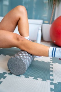 Person's legs performing self myofascial release actively with a foam roller, focusing on muscle
