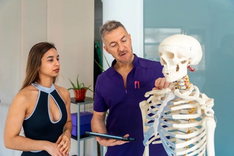 Experienced osteopath or physiotherapist showing a female patient spinal anatomy on a human