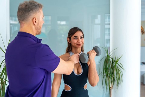 Physiotherapist male trainer assisting a young woman client with rehabilitation and strength