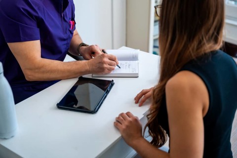 Medical professional, possibly an osteopath or physiotherapist, discussing treatment plans and