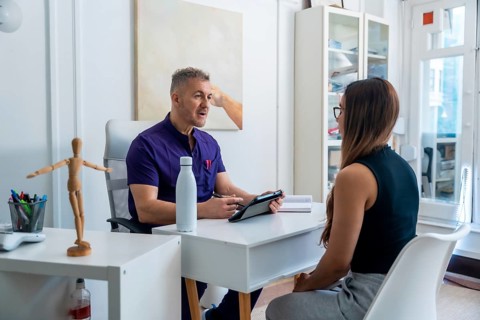 Medical professional wearing scrubs discussing therapy options and recovery plans with a female