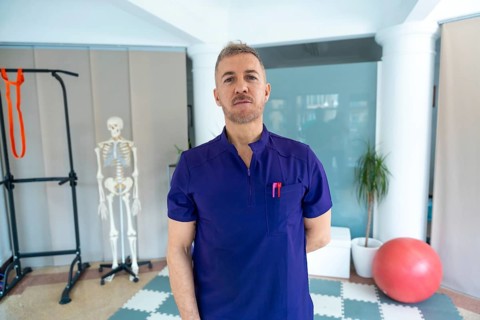 Physiotherapist standing confidently in a modern recovery clinic, offering sports osteopathy and