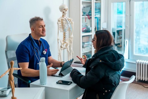 Doctor in blue scrubs and stethoscope consulting a female patient regarding her health concerns,