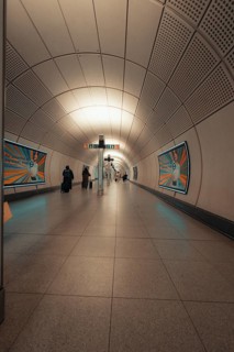 Modern subway tunnel with few passers-by and posters on the walls, London, Great Britain