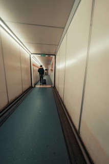 Long airport aisle with a traveller pulling a trolley bag, London, United Kingdom