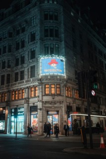 Illuminated theatre building at night with advertisement for a performance, London, Great Britain