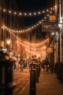 Evening street scene with fairy lights and people strolling in a city, London, Great Britain