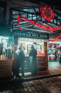 Market stall at night, decorated with Christmas lights, with people in front of it, London, Great