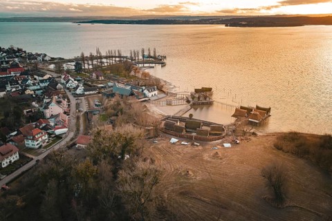 Panorama of a village with stilt houses on the lakeside at sunset, captured in warm light, stilt
