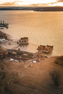 Historic stilt houses on the shore of a lake at sunset with warm light and peaceful atmosphere,