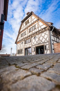 Timbered house with steep roof line against blue sky and cobblestone road, Ötisheim, Enzkreis,