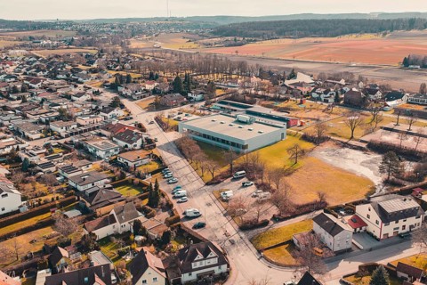Bird's eye view of a village with buildings and natural fields in the background, Ötisheim,