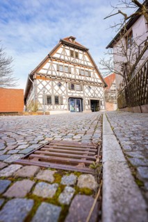Half-timbered house with cobblestone street and wooden fence in a historic setting, Ötisheim,